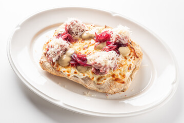 Savory toast with melted brie, red onions, and creamy sauce, topped with shredded meat or cheese. A gourmet appetizer or meal on a white plate.