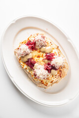Savory toast with melted brie, red onions, and creamy sauce, topped with shredded meat or cheese. A gourmet appetizer or meal on a white plate.