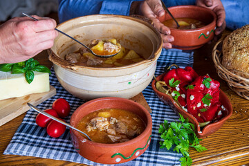 A warm bowl of cooked potato soup placed on a table, showcasing its creamy texture, soft vegetables, and homemade appearance. The natural lighting highlights the comforting and rustic feel of the dish