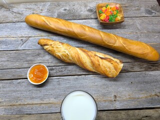 tasty pieces of baguette lie on a wooden table next to a cup of milk