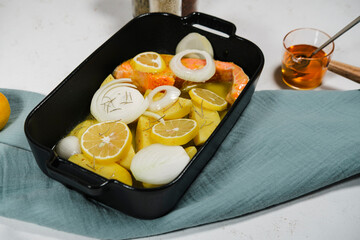 raw salmon, potatoes, sliced onions, lemons, honey mustard saused fish ready to be cooked in oven