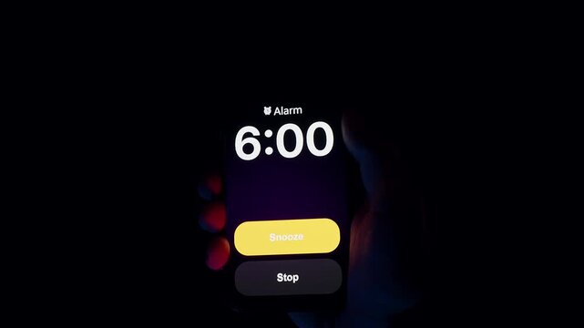 Smartphone Screen Displays Alarm Set for 6 AM Held in Hand Under Blue and Red Light in Dark Room Environment