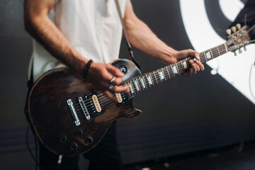Concert view of an electric guitar player with vocalist and rock band performing in a club, male...