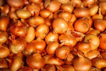 Close-up of golden onions piled together, showcasing natural texture and warm earthy tones. Fresh organic vegetables from local market symbolizing healthy food and agriculture.
