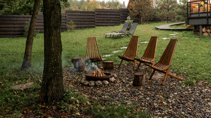 Cozy outdoor seating area with a fire pit and wooden chairs in a backyard setting