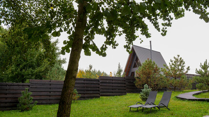 Modern A-frame cabin with lounge chairs on a green lawn