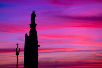 The silhouette of a religious statue stands against a winter sunset, where deep blues and soft pinks blend into violet. Sameiro Sanctuary, Braga, Portugal. © bruno ismael alves