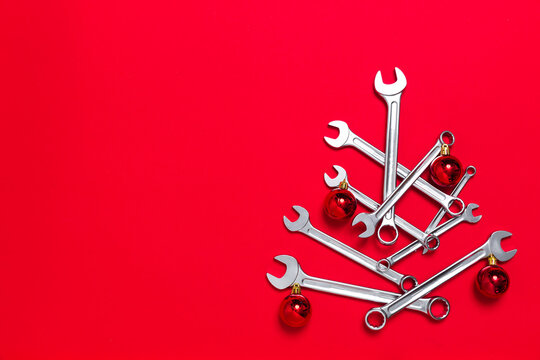 Creative christmas tree made of wrenches decorated with balls on red background. New Year banner with wrenches. Postcard with place for greeting text with industrial holiday concept. Flat lay layout.