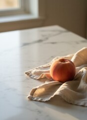 A single ripe peach on a linen napkin in a minimalist still life. Fresh fruit on a white marble countertop with soft natural light. Healthy food concept with copy space