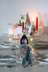 Table set for Christmas meal, with plates, wine, decorations and lit candles. Selective focus.