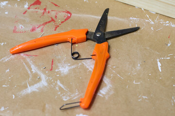 A detailed close-up of orange handled pruning shears laying on a brown paper surface, showcasing...
