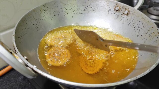 Close up video of traditional Indian snack Chakli being deep fried in hot oil. It is known as Chakali, Murukku, Muruku, Murkoo, Chakri.