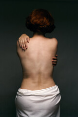 Elegant woman with short hair covering bare back, wrapped in soft white fabric