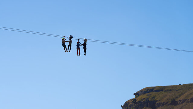 Ziplining. Attraction staff help two women who got stuck on a rope while descending over a gorge to the finish line. - Powered by Adobe