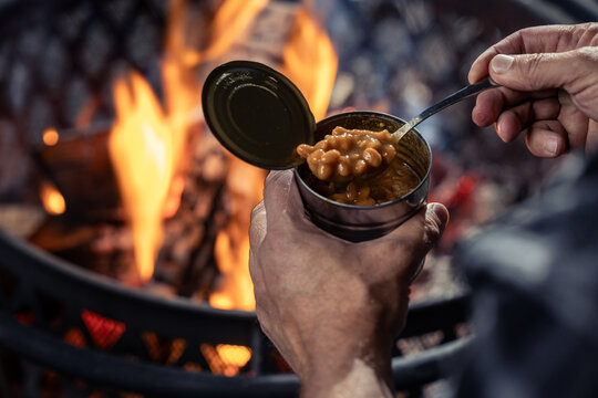 Hands holding a can of baked beans by the fire