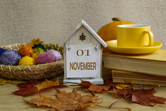 November 1st Calendar: a decorative calendar with the numbers 01, the month's name in English, colorful yarn, and a cup of tea with autumn leaves