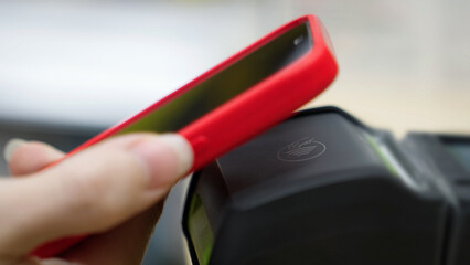Contactless payment. Paying for a purchase with a smartphone using a contactless NFC terminal. Shopping at a mall, secure financial transaction. Close-up of a mobile phone.