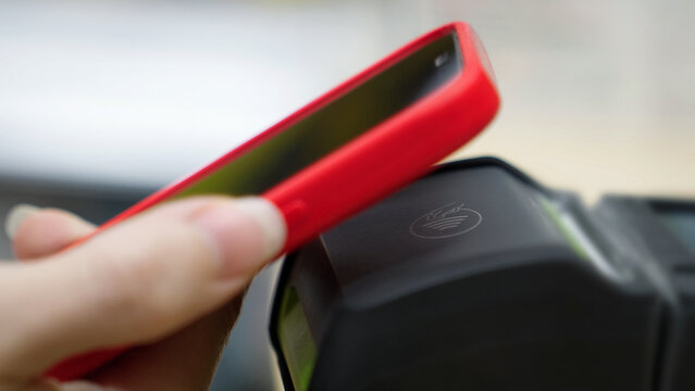 Contactless payment. Paying for a purchase with a smartphone using a contactless NFC terminal. Shopping at a mall, secure financial transaction. Close-up of a mobile phone.