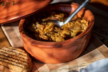 A bowl of cooked cabbage served in a rustic brown dish, showcasing its soft texture and warm, comforting appearance. The natural colors and simple presentation make this image suitable for traditional