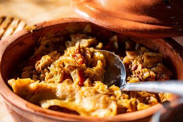A bowl of cooked cabbage served in a rustic brown dish, showcasing its soft texture and warm, comforting appearance. The natural colors and simple presentation make this image suitable for traditional