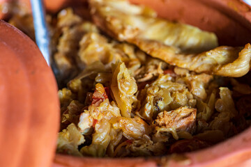 A bowl of cooked cabbage served in a rustic brown dish, showcasing its soft texture and warm, comforting appearance. The natural colors and simple presentation make this image suitable for traditional