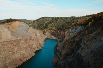 Fototapeta premium Scenic view of blue water lake in rocky quarry surrounded by colorful autumn forest and hills in Fruska Gora Serbia