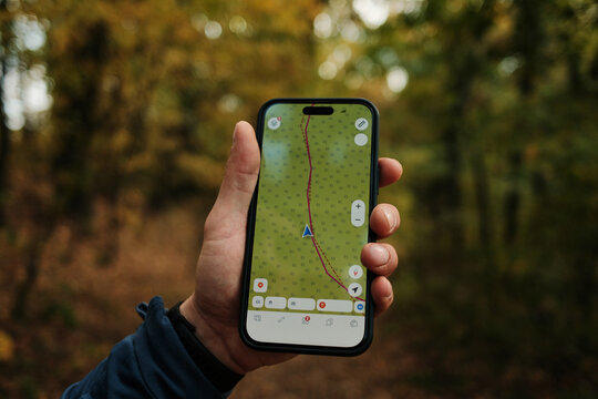Close-up of man holding smartphone with GPS navigation app while hiking in autumn forest of Fruska Gora National Park Serbia. Travel concept - Powered by Adobe