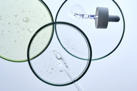 Three petri dishes with different serums and pipettes.