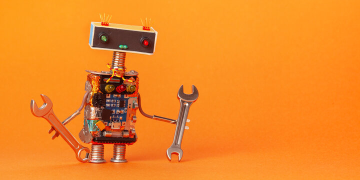 A toy mechanical robot holds repair tools. A robot mechanic handyman repairman character with a hand wrench. Orange background.