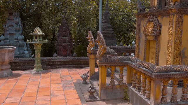 Massive golden stupa with statues of Yakshas demon guardians on its levels stand in the temple grounds of Wat Svay Romeat Pagoda in Siem Reap, Cambodia. Shot in motion