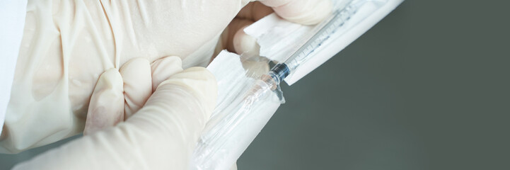 Close-up of medical professional preparing syringe with protective gloves in clean clinical setting.