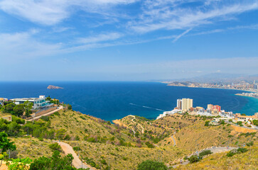 Aerial panoramic view of Benidorm bay Mediterranean Sea azure water with Isla de Benidorm island, Costa Blanca coastline Benidorm city coast, buildings in Serra Gelada park in summer day, Spain