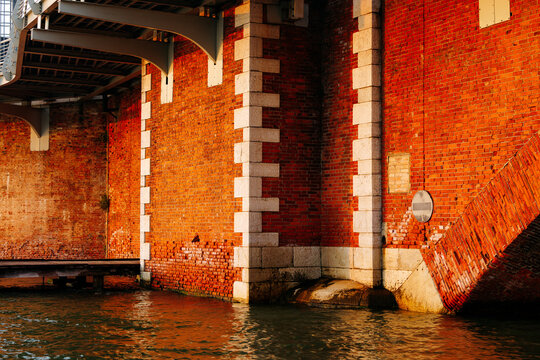 Historic red brick bridge over water with architectural details at sunset - Powered by Adobe