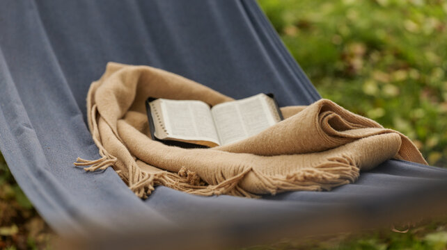 Bible resting in a hammock with a cozy blanket on a relaxing day