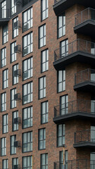 Fototapeta premium Modern apartment building exterior with brick facade and balconies