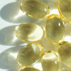 Shiny transparent yellow capsules with light reflections on white background.