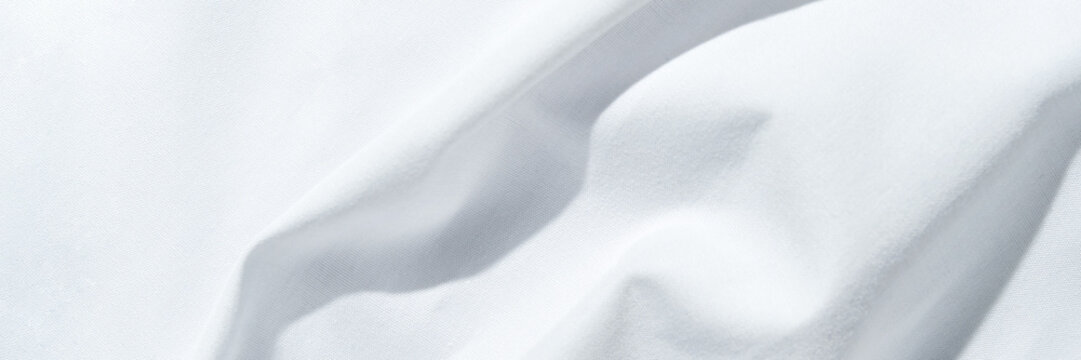 Crisp white fabric with gentle folds and soft textures in natural light.
