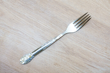 Unique silver fork with intricate design resting on wooden surface