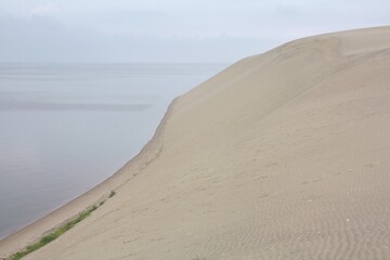 Parnidis dune. Background. A massive sand dune. Slopes down to the tranquil waters of the Curonian lagoon. Creating a minimalist landscape in Russian Curonian Spit national park. Travel tour