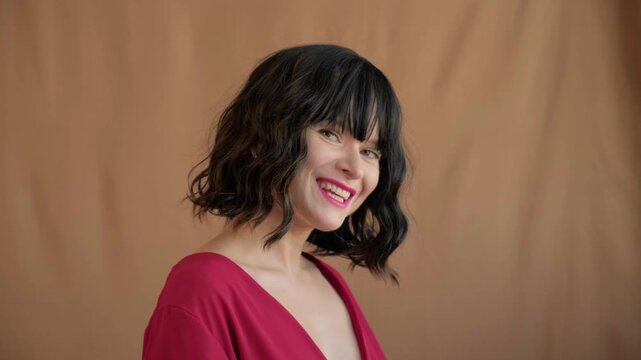 Beautiful woman laughs with bright teeth smile in red top, playful expression. Red lipstick make-up and wavy bob hair. Lifestyle, fashion, beauty and happiness themes. Style for holidays or date