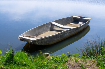 Obraz premium Peaceful rowboat rests on calm waters in sunlit scene