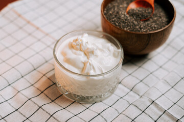 Roasted chia seeds beside a bowl of yogurt on a checkered cloth