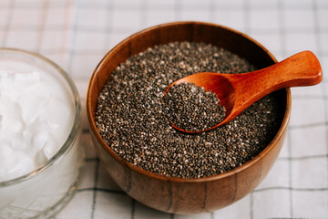 Roasted chia seeds in a wooden bowl with a spoon on a checkered tablecloth