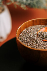 Roasted chia seeds in a wooden bowl with a spoon on a simple table