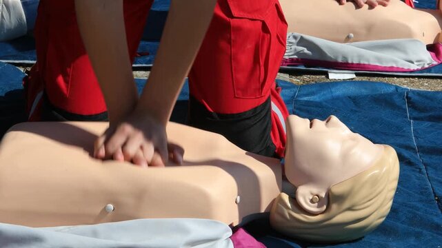 Cardiopulmonary resuscitation (CPR) training demonstration showing paramedic performing chest compressions on adult CPR dummy during first aid course