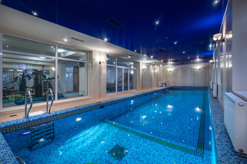 Indoor swimming pool with modern design and amenities in a luxury facility during the evening hours