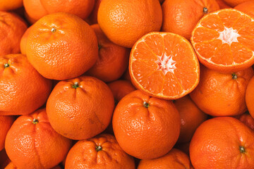 Fresh tangerines with one cut fruit showing juicy pulp. The picture conveys the concept of natural...