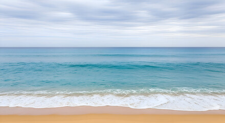 Obraz premium A serene ocean landscape with gentle waves lapping on a sandy beach under a cloudy sky