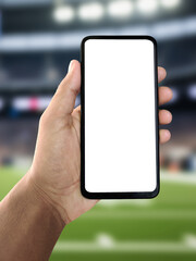 Hand holding smartphone with playground or sports background mockup, football and cricket field visible, sports app interface concept, digital athletics and outdoor game technology idea, active lifest