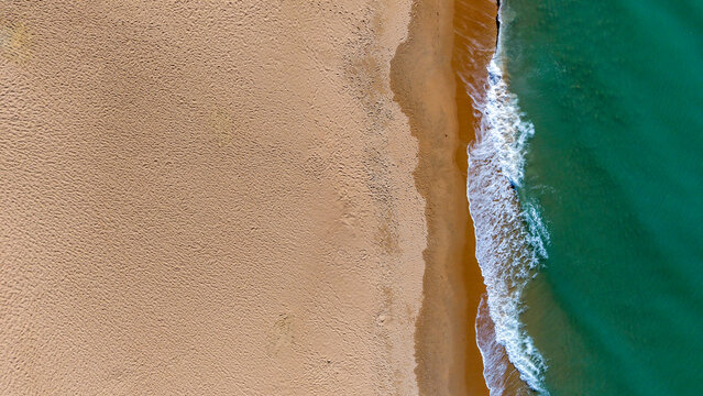 vista a&eacute;rea de de las olas rompiendo en la arena de la costa